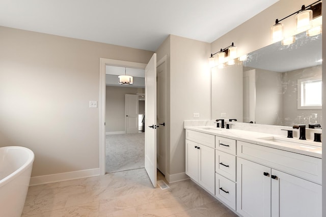 full bathroom featuring double vanity, marble finish floor, a freestanding bath, and a sink