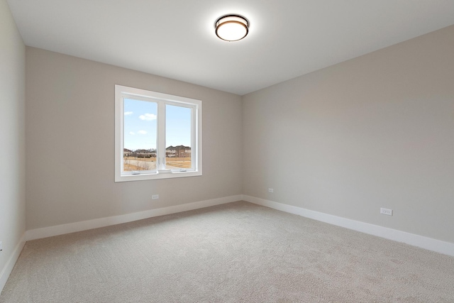 unfurnished room featuring light carpet and baseboards