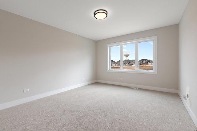 spare room featuring light colored carpet, visible vents, and baseboards