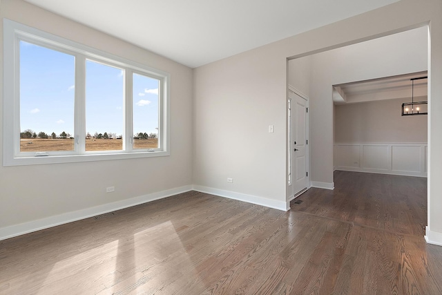 unfurnished room with wood finished floors, visible vents, and baseboards