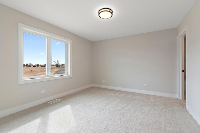 empty room with light colored carpet, visible vents, and baseboards