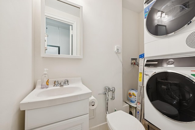 bathroom featuring stacked washer / dryer, vanity, and toilet