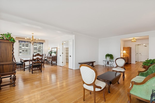 living room featuring light wood finished floors, a chandelier, and crown molding