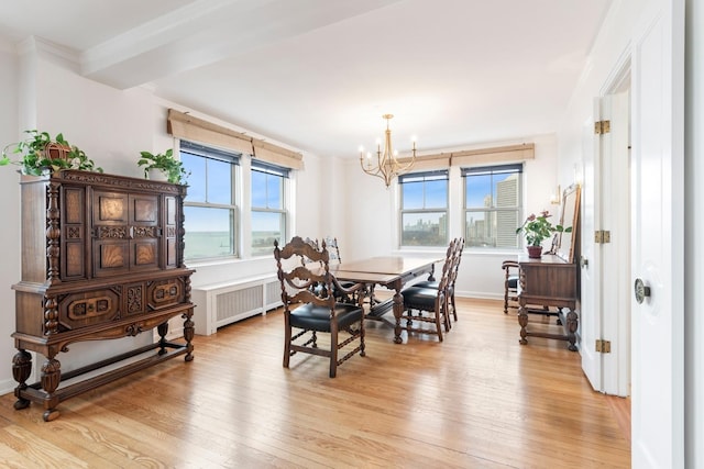 dining room featuring light wood-style floors, radiator, crown molding, and an inviting chandelier