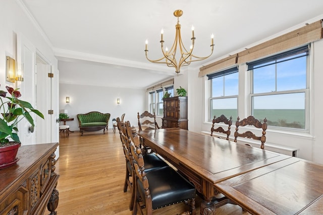 dining area with crown molding, a notable chandelier, and light wood finished floors