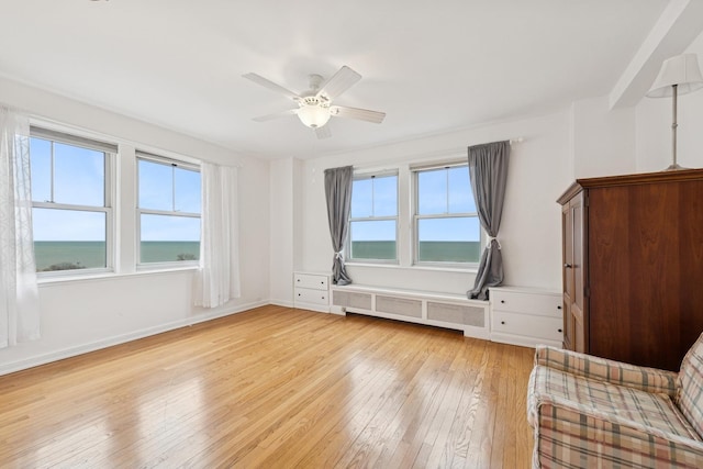 unfurnished room featuring radiator, a healthy amount of sunlight, ceiling fan, and light wood finished floors