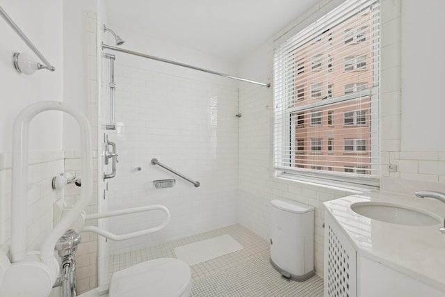 full bathroom with tiled shower, tile walls, and toilet