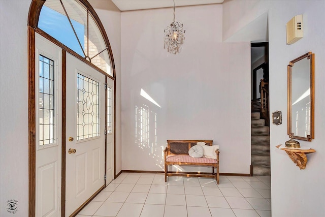 foyer entrance with light tile patterned floors, baseboards, stairs, and a chandelier