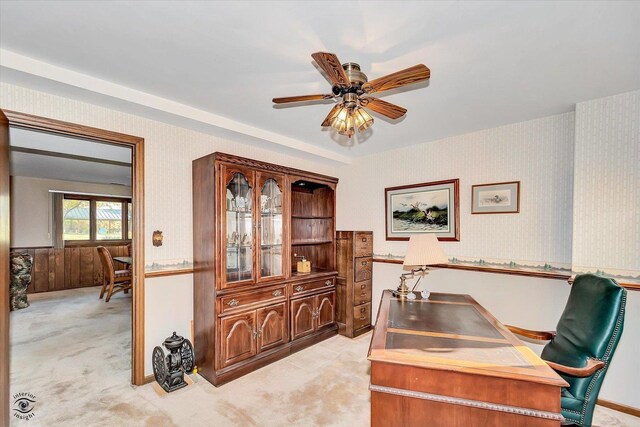 office space with a ceiling fan, wainscoting, light colored carpet, and wallpapered walls