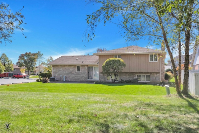 back of property with brick siding, a yard, and central air condition unit