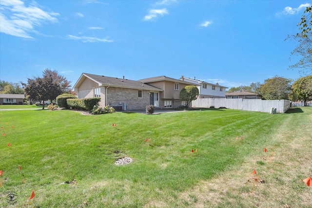 back of house featuring a patio area, central AC, fence, and a lawn