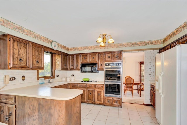 kitchen featuring light countertops, a sink, white appliances, a peninsula, and wallpapered walls