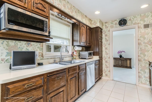 kitchen with appliances with stainless steel finishes, a sink, visible vents, and wallpapered walls