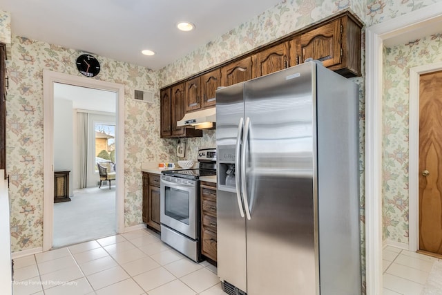 kitchen featuring wallpapered walls, light tile patterned floors, under cabinet range hood, and stainless steel appliances