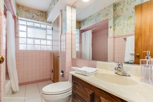 full bathroom featuring tile walls, wallpapered walls, toilet, wainscoting, and tile patterned floors