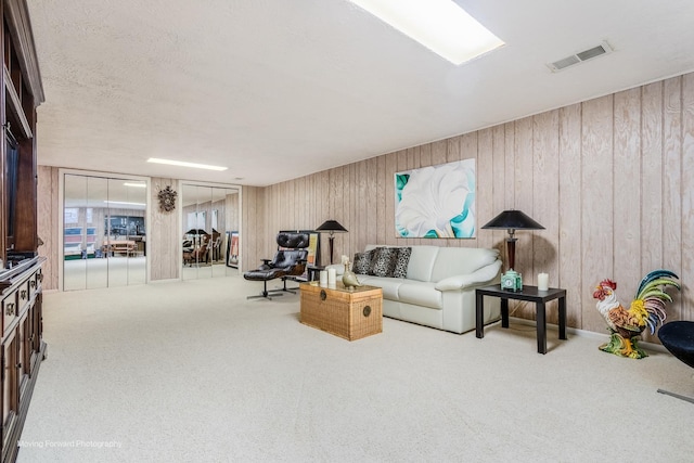 living room with carpet floors, wood walls, and visible vents