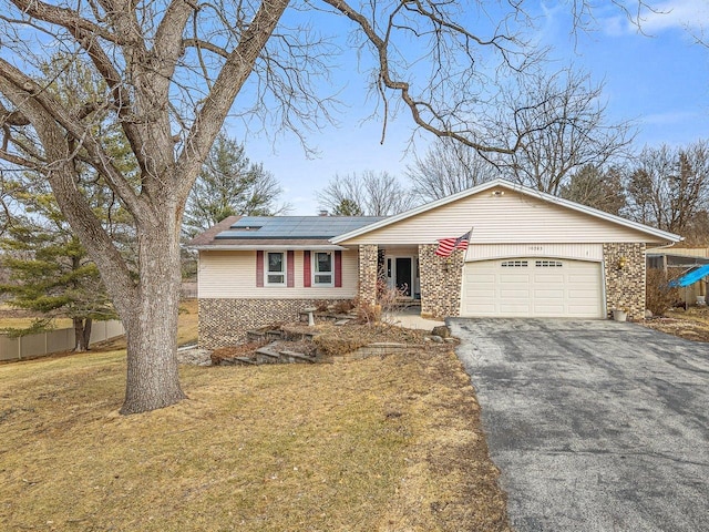 ranch-style home with fence, a front yard, roof mounted solar panels, a garage, and driveway