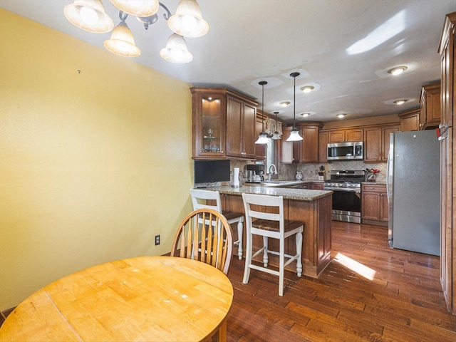 kitchen with a peninsula, stainless steel appliances, decorative backsplash, dark wood-type flooring, and glass insert cabinets