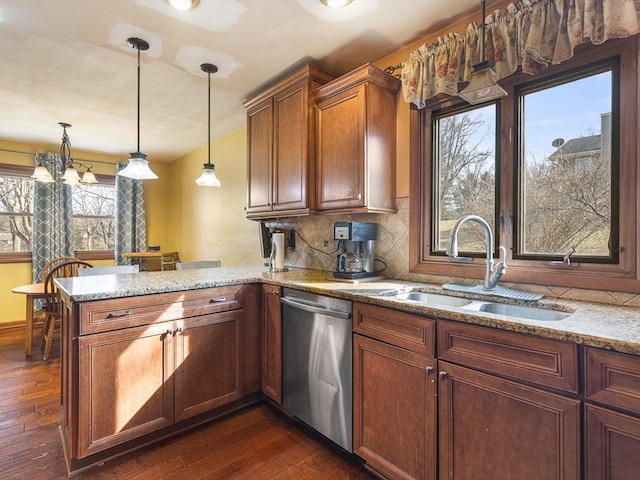 kitchen with light stone counters, dishwasher, a peninsula, and a sink