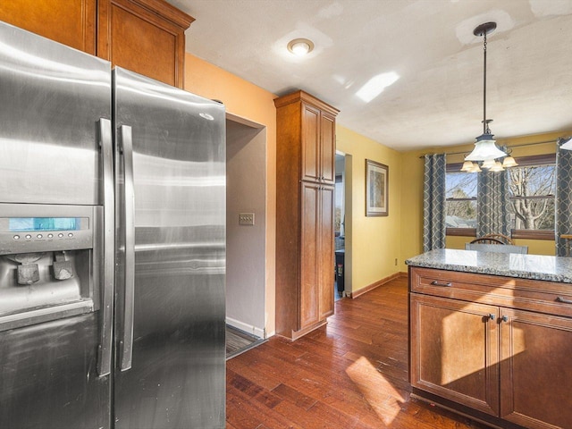 kitchen with dark wood-type flooring, baseboards, stainless steel fridge with ice dispenser, light stone counters, and brown cabinets