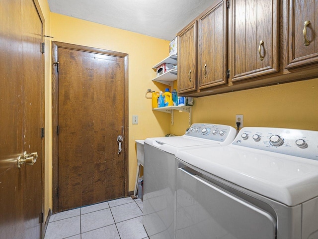 laundry area featuring cabinet space, light tile patterned floors, and washing machine and dryer