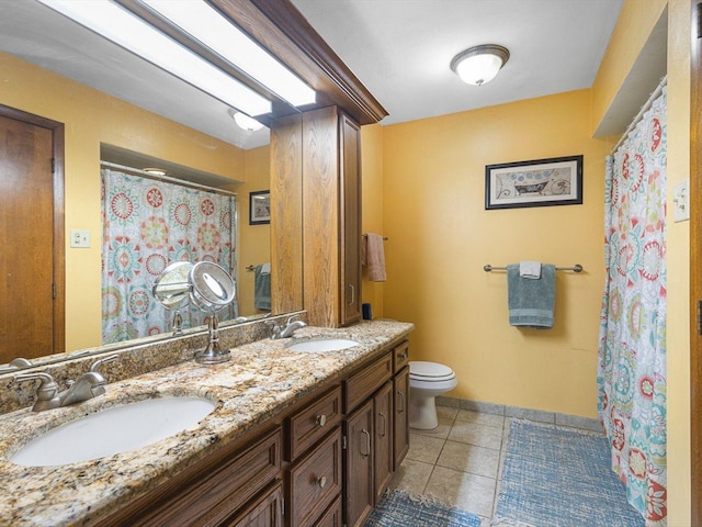 full bathroom with tile patterned floors, toilet, double vanity, and a sink