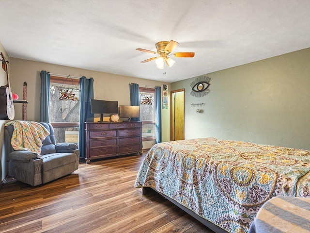 bedroom with a ceiling fan, multiple windows, and wood finished floors