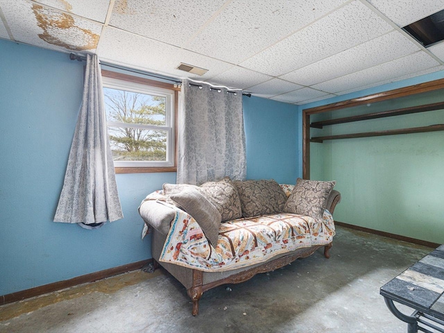 sitting room with a paneled ceiling, visible vents, concrete floors, and baseboards