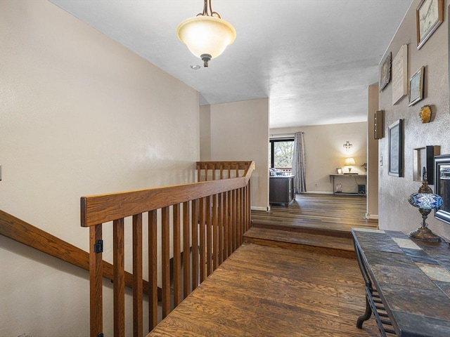 hallway with baseboards, an upstairs landing, and wood finished floors