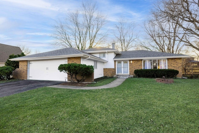 split level home with aphalt driveway, brick siding, a chimney, a garage, and a front lawn