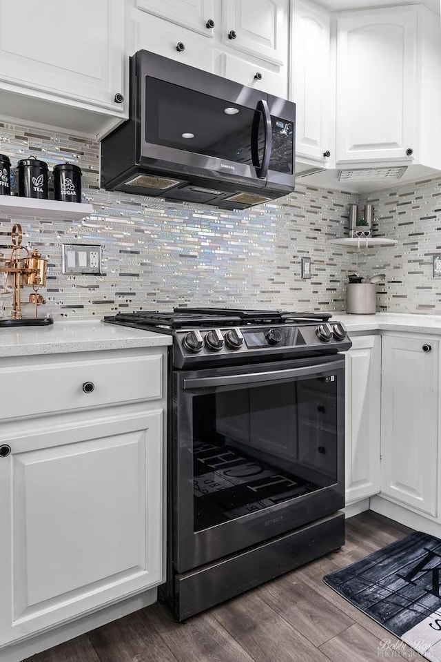 kitchen featuring decorative backsplash, appliances with stainless steel finishes, white cabinetry, and dark wood-type flooring