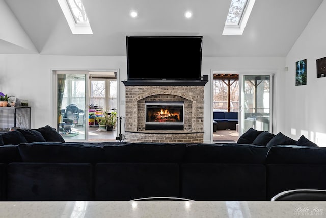 living area with recessed lighting, vaulted ceiling with skylight, and a fireplace