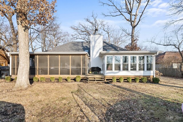 back of property with fence, a chimney, and a sunroom