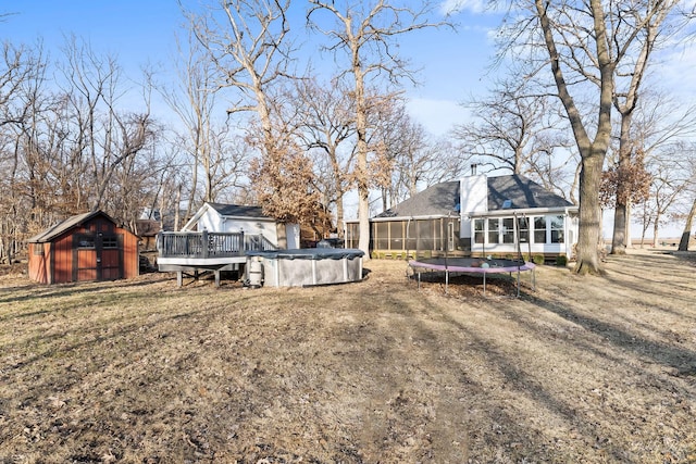 view of yard featuring a covered pool, a trampoline, a storage shed, an outdoor structure, and a sunroom