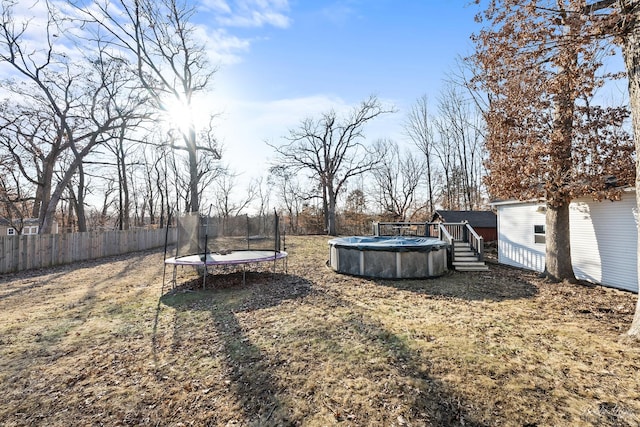 view of yard with a fenced in pool, a trampoline, and fence