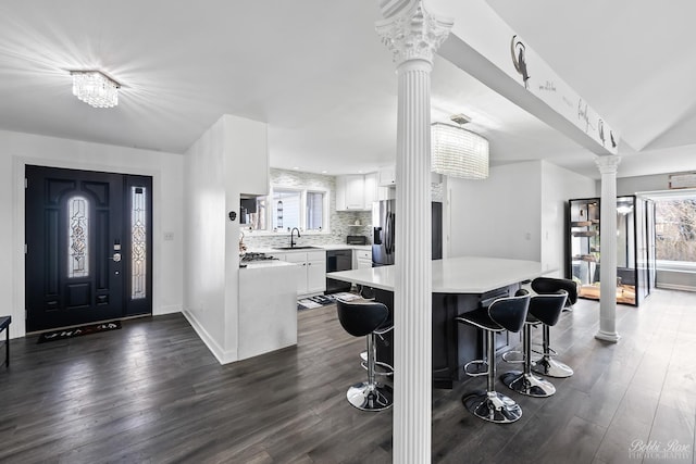 interior space with baseboards, dark wood-style flooring, and ornate columns