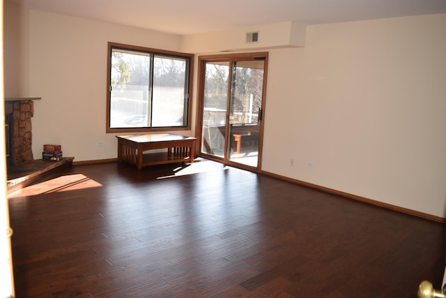 spare room featuring baseboards, a fireplace, visible vents, and wood finished floors