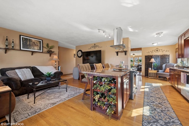 kitchen featuring light stone counters, open floor plan, light wood-style flooring, and island range hood