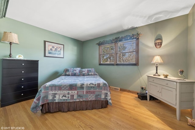 bedroom with visible vents, baseboards, and wood finished floors