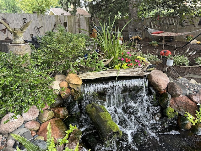 exterior details with a garden, fence, and a small pond