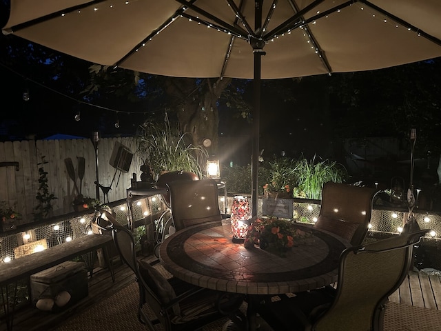 patio at twilight with outdoor dining space and fence