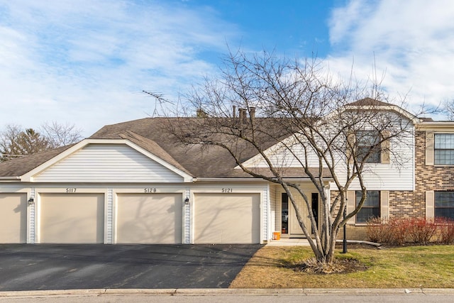 view of front of property with a shingled roof, brick siding, and community garages