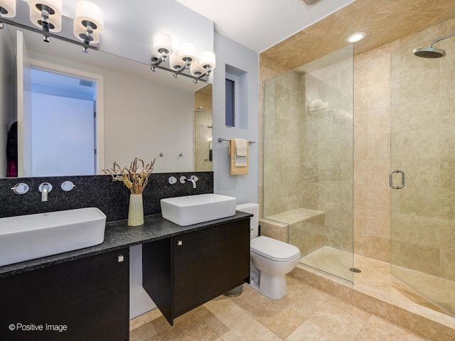 bathroom featuring toilet, a shower stall, backsplash, and a sink