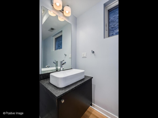 bathroom with baseboards, visible vents, wood finished floors, and vanity