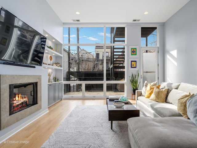 living area with light wood-style flooring, expansive windows, visible vents, and a fireplace