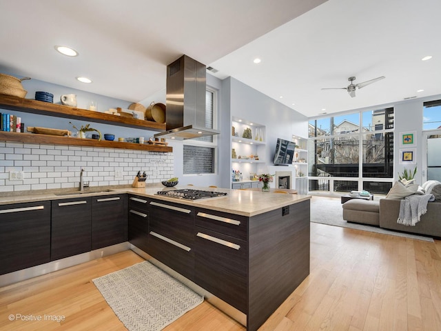 kitchen featuring a sink, light countertops, range hood, modern cabinets, and stainless steel gas stovetop