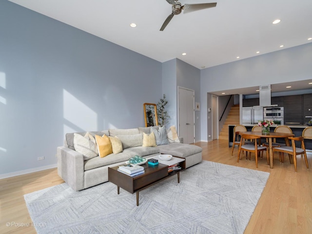 living room featuring light wood-style floors, recessed lighting, and stairs