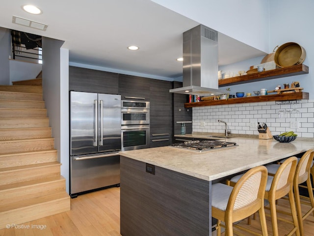 kitchen featuring island exhaust hood, visible vents, appliances with stainless steel finishes, modern cabinets, and a peninsula