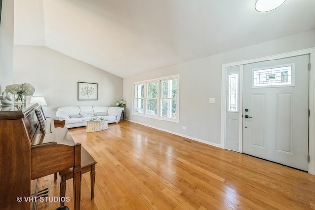 interior space with visible vents, baseboards, light wood-style flooring, and vaulted ceiling