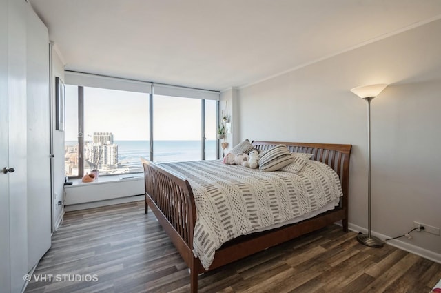 bedroom with a water view, wood finished floors, crown molding, and access to outside